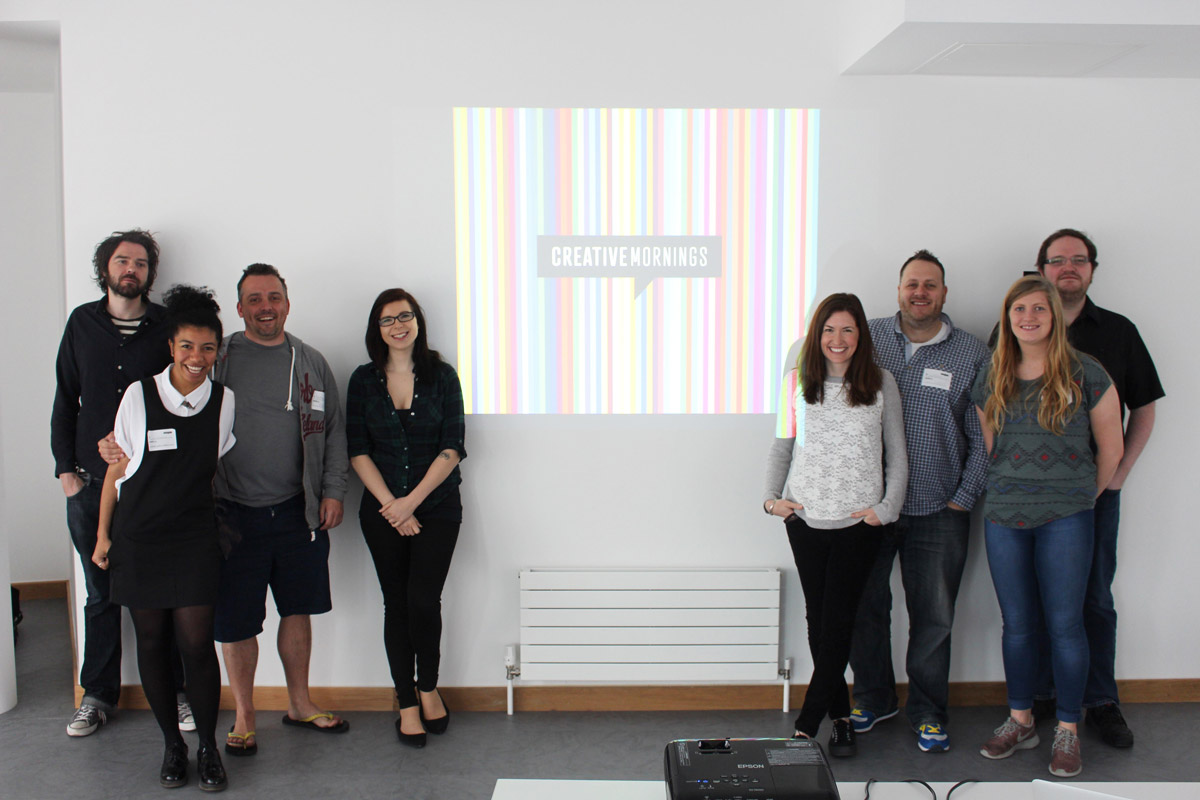 One of the first CreativeMorning/Cardiff teams standing around the CreativeMornings logo